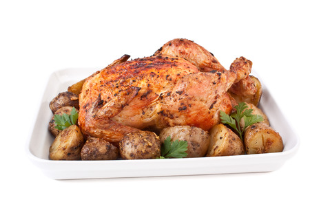 whole golden roasted chicken with roasted potatoes and parsley isolatedの写真素材