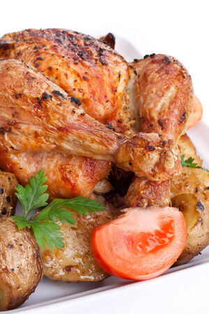 whole golden roasted chicken with roasted potatoes, fresh tomatoes and parsleyの写真素材