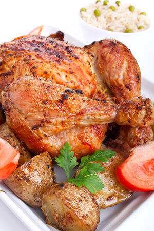 whole golden roasted chicken with roasted potatoes, fresh tomatoes and rice with peasの写真素材