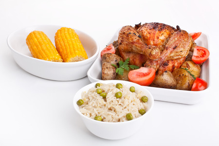 whole golden roasted chicken with roasted potatoes, fresh tomatoes, corn and rice with peasの写真素材