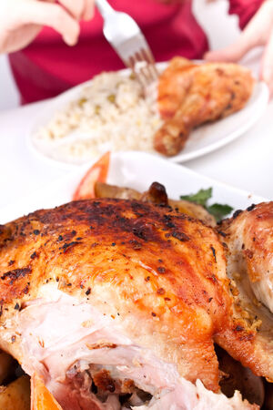 woman eating a chicken leg just cut off a whole chickenの写真素材