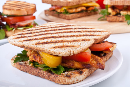 grilled chicken sandwich on a white plate with three other at the backの写真素材