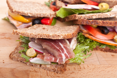 group of big healthy sandwiches made with whole grain bread, lettuce, vegetables and meatの写真素材