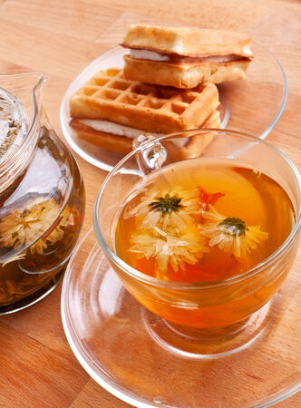 glass cup with chrysanthemum green tea, waffles and tea-potの写真素材