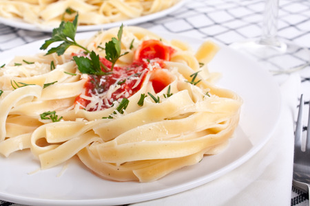 servings of taghliatelle pasta with tomato sauce, cheese and parsleyの写真素材