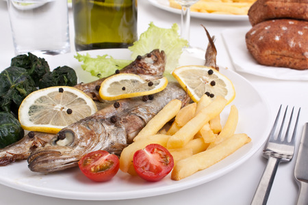 serving of grilled Blue whiting fish with lemon, pepper and fried spinachの写真素材