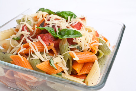 serving of colored penne pasta with tomato sauce, cheese and basilの写真素材