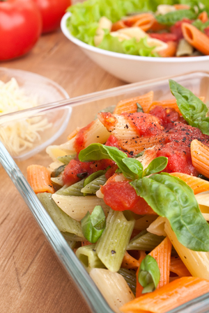 two servings of colored penne pasta with tomato sauce and basilの写真素材