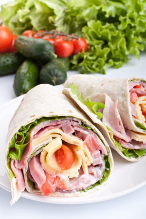 wrapped tortilla sandwich rolls cut in half with ingredientsの写真素材