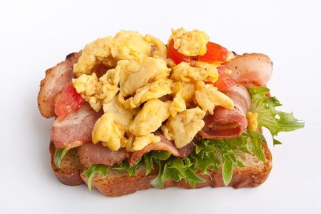 hot sandwich with fried bacon, scrambled eggs and lettuce on white backgroundの写真素材