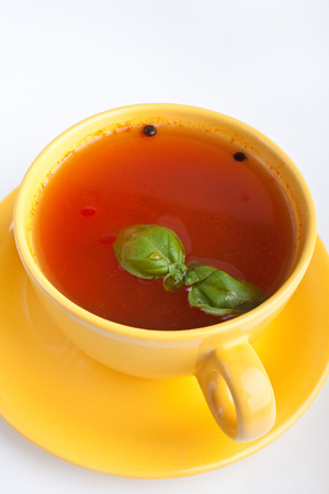 tomato soup in yellow cup on white backgroundの写真素材