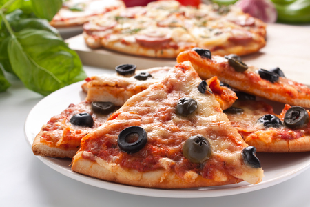 sliced sausage and black olive pizzas with ingredientsの写真素材