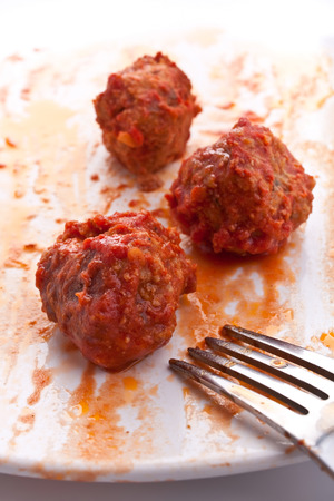 three tomato meatballs on a plate with a forkの写真素材