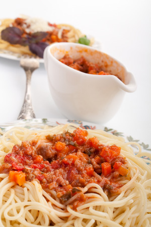 two servings of spaghetti bolognese and a sauce boatの写真素材