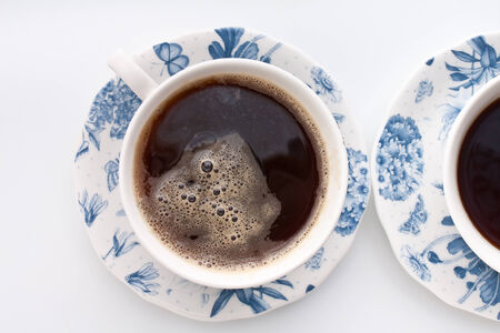 two cups of coffee in white and blue floral patterned chinaの写真素材