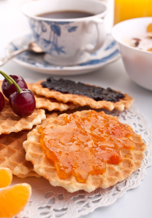 cup of coffee with waffles and orange and cherry jamの写真素材