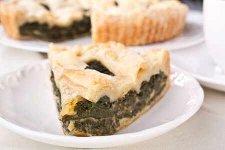 piece of cheese and spinach pie on white plateの写真素材