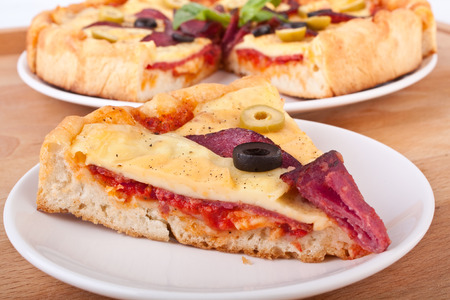 pepperoni pizza slice with olives on whiteの写真素材