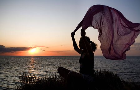 girl with scarf, silhouette at sunsetの写真素材