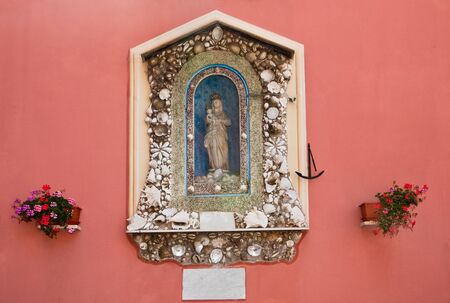 Icon of the Madonna with the baby decorated with sea cockleshells on the wall in an ancient fishing small village Camogliの写真素材
