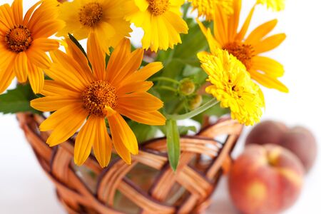 Basket of yellow flowers next to   two peachの写真素材