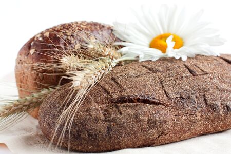 Two loaves of bread and wheat ears, closeup