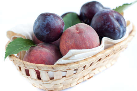 Ripe peaches and plums in the basket, closeupの写真素材