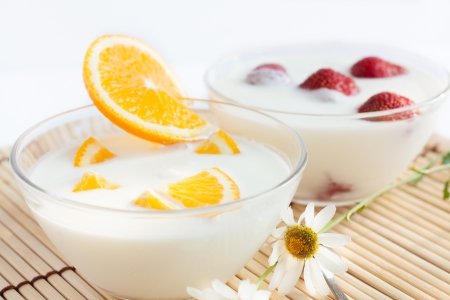 Strawberry yogurt and orange in transparent bowlsの写真素材