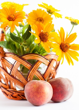 Basket of flowers and two ripe peaches, close upの写真素材