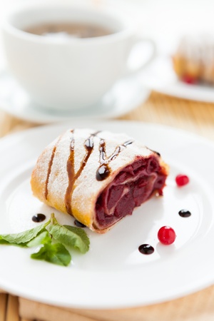 cherry strudel on white plate and a cup of tea, dessertの写真素材