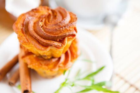 two cupcakes on a white plate and cinnamon sticks, closeup