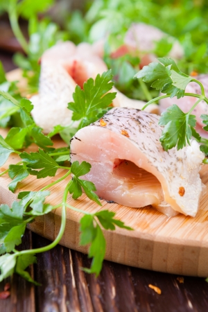 pike fillet pieces on a cutting board and a sprig of parsley, closeupの写真素材