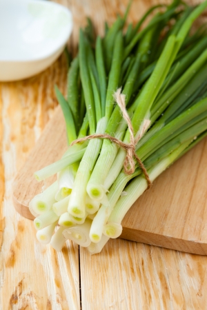 bunch of fresh green onions on a wooden surface, closeupの写真素材