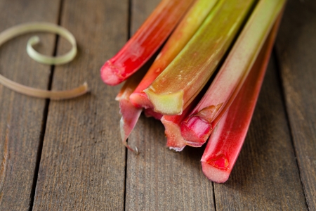 raw rhubarb stalks on a wooden surface, food close upの写真素材