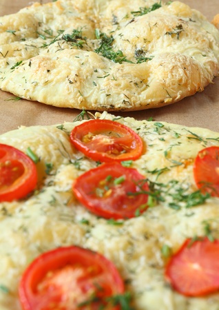 Italian focaccia (pizza) with tomatoes and herbs, food close up