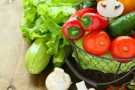 mix vegetables inside a black basket on wooden tableの写真素材