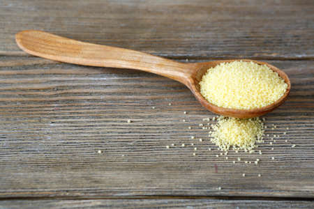 Couscous in a wooden spoon on boards, food close upの写真素材