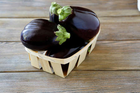 Heap of eggplant in a box, wooden backgroundの写真素材