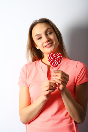 Smiling girl holding a red candy in the hands of a heart-shaped Valentine's Dayの写真素材