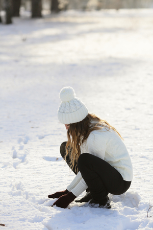 Girl in the snow sitting in the park playing with snowの写真素材