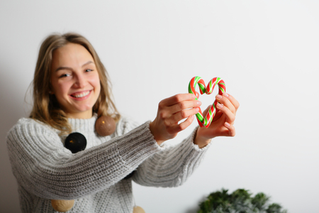Smiling positive young woman holding Christmas candiesの写真素材