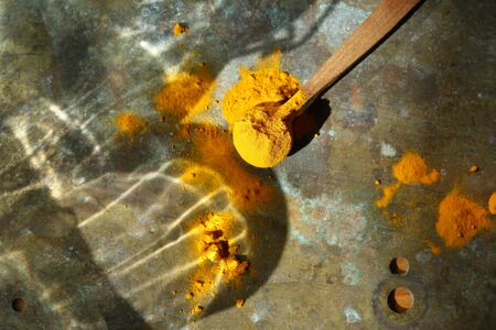 Turmeric powder on wood spoon aboveの写真素材