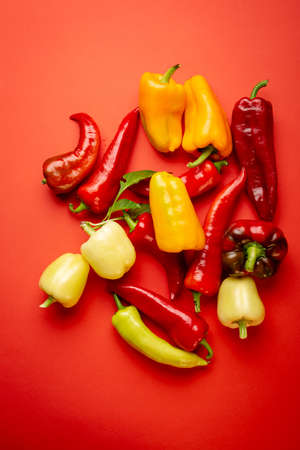 Red and yellow paprika on red surfaceの写真素材