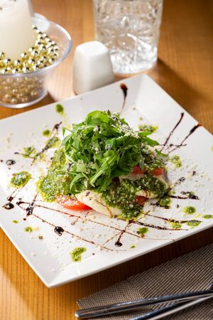 Caprese salad with pesto sauce close-up on plateの写真素材