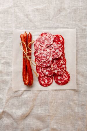 Sliced pork salami and sausage on white paperの写真素材