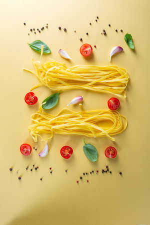 Set of pasta ingredients on yellow bold surfaceの写真素材