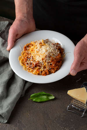 Pasta with bolognese sauce in menâs handsの写真素材