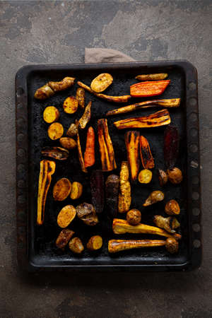 Overhead view of roasted roots on black baking sheet
