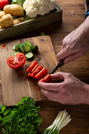 Men hand cutting red tomato on kitchen boardの写真素材