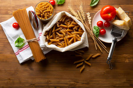 Whole grain uncooked pasta on wooden tableの写真素材